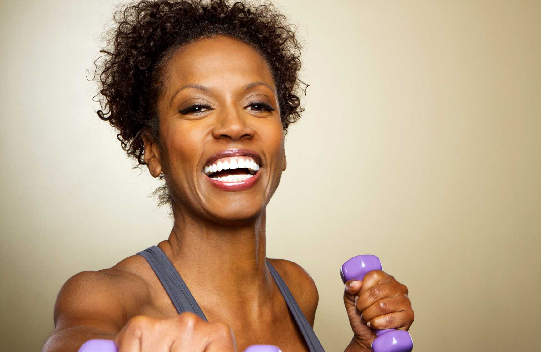 Smiling woman holding purple dumbbells.