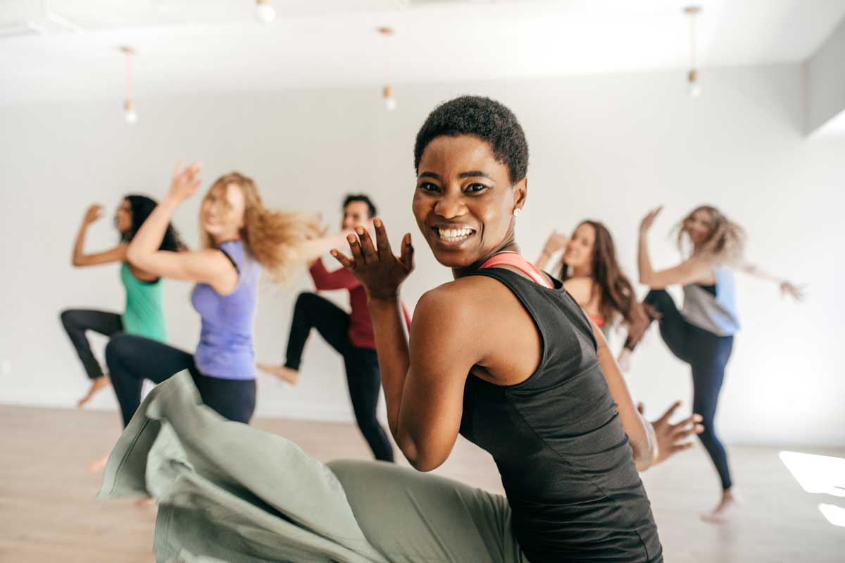 A diverse group of people participating in a high-energy Zumba class, with the instructor leading the group in dance movements.