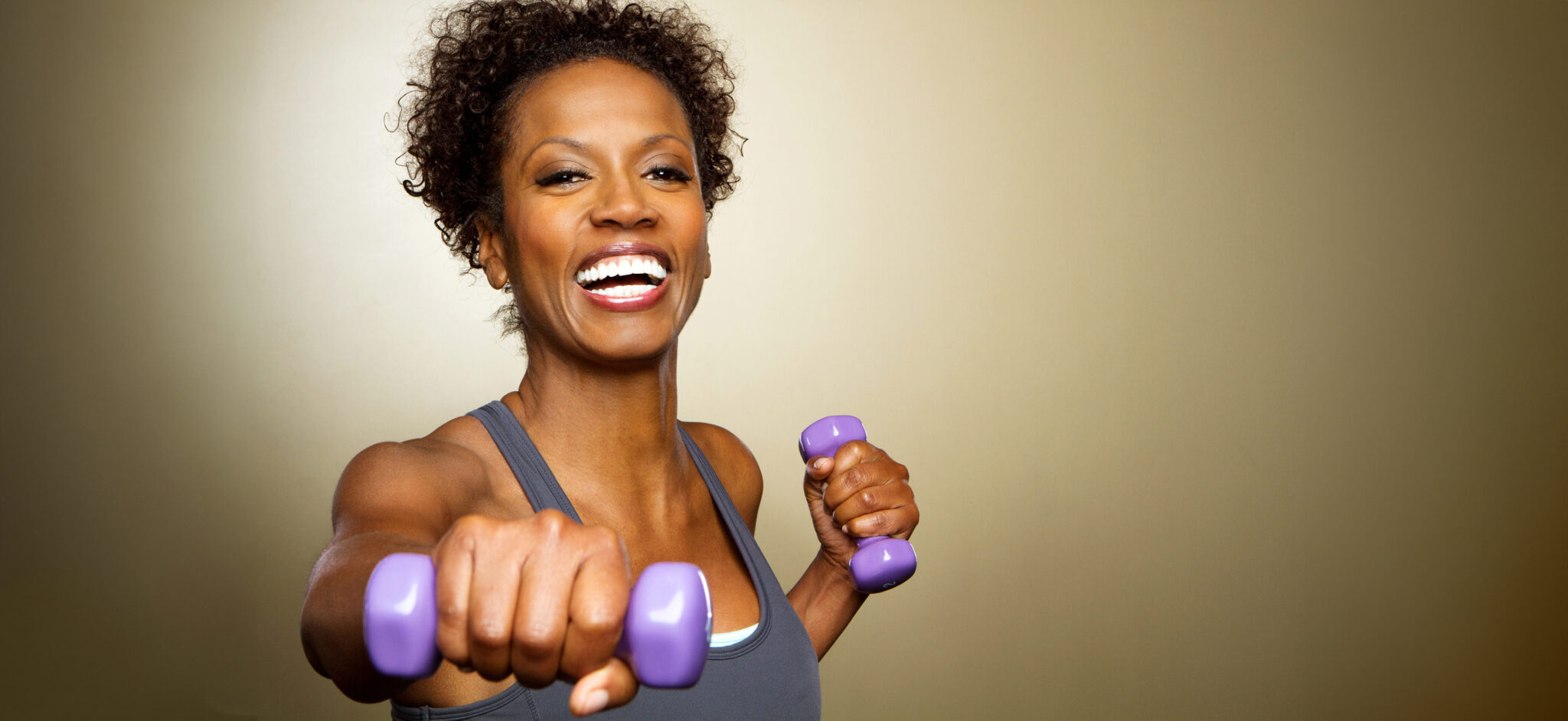 Smiling woman holding purple dumbbells.