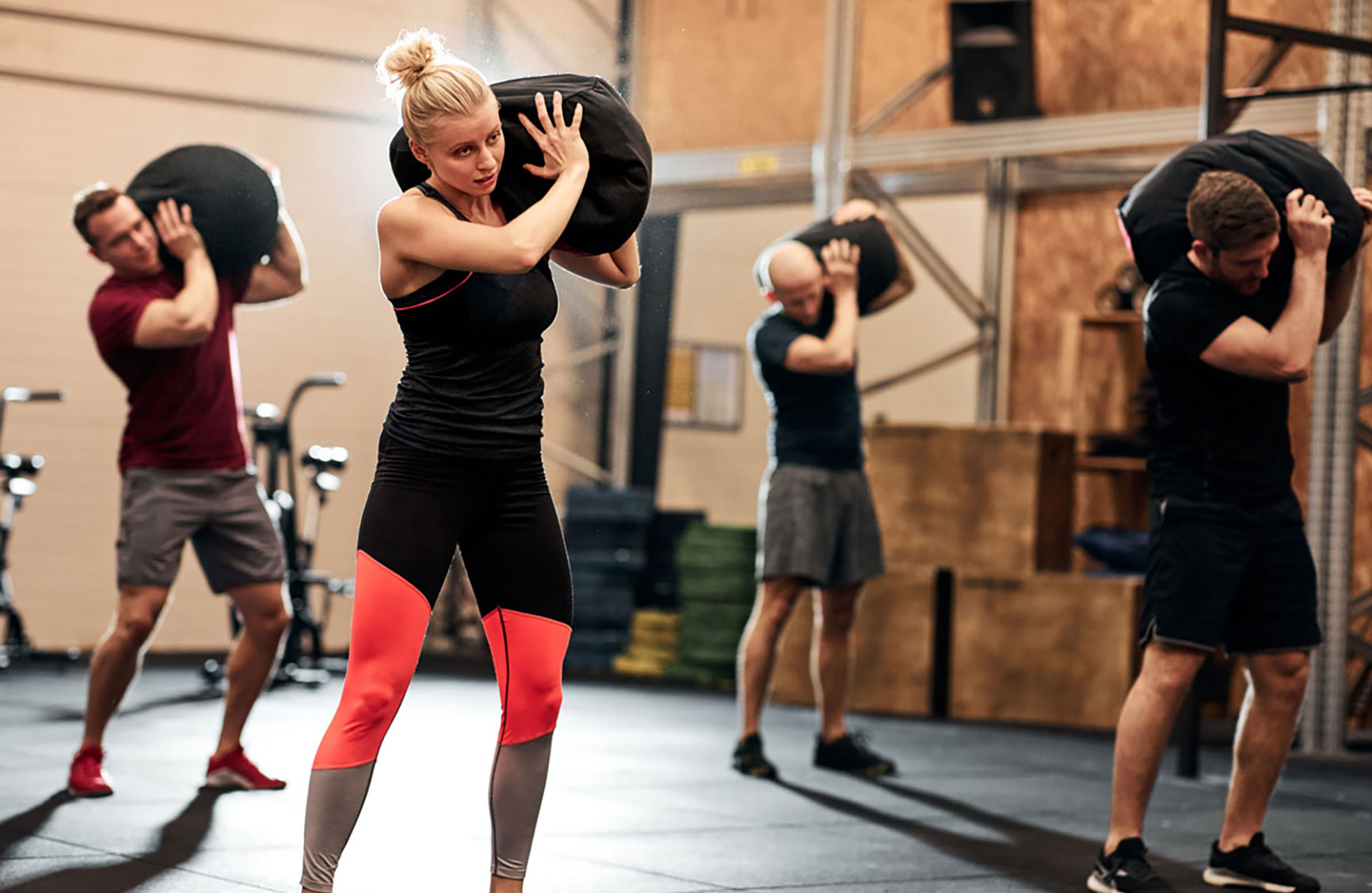 A group of people lifting weighted bags during a workout in a fitness studio.