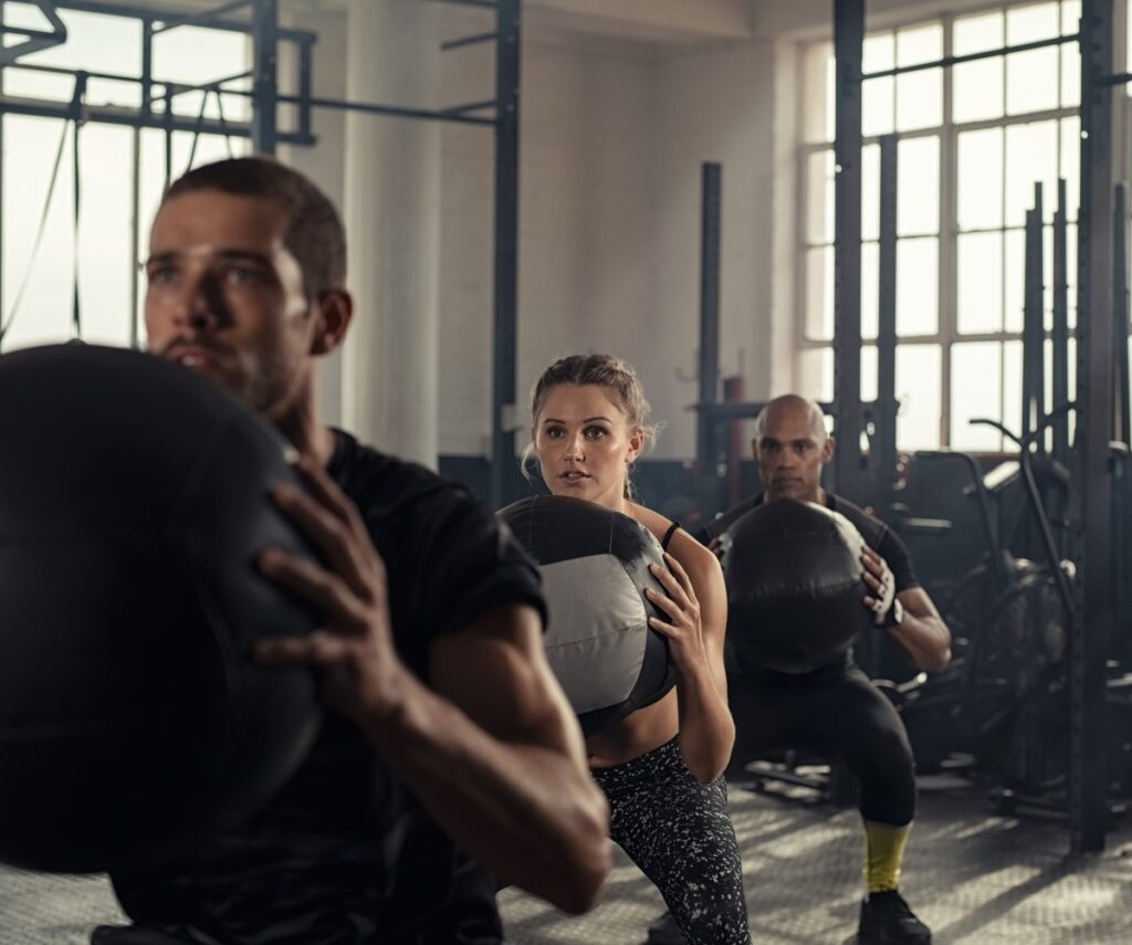 Three people exercising with a medicine ball.